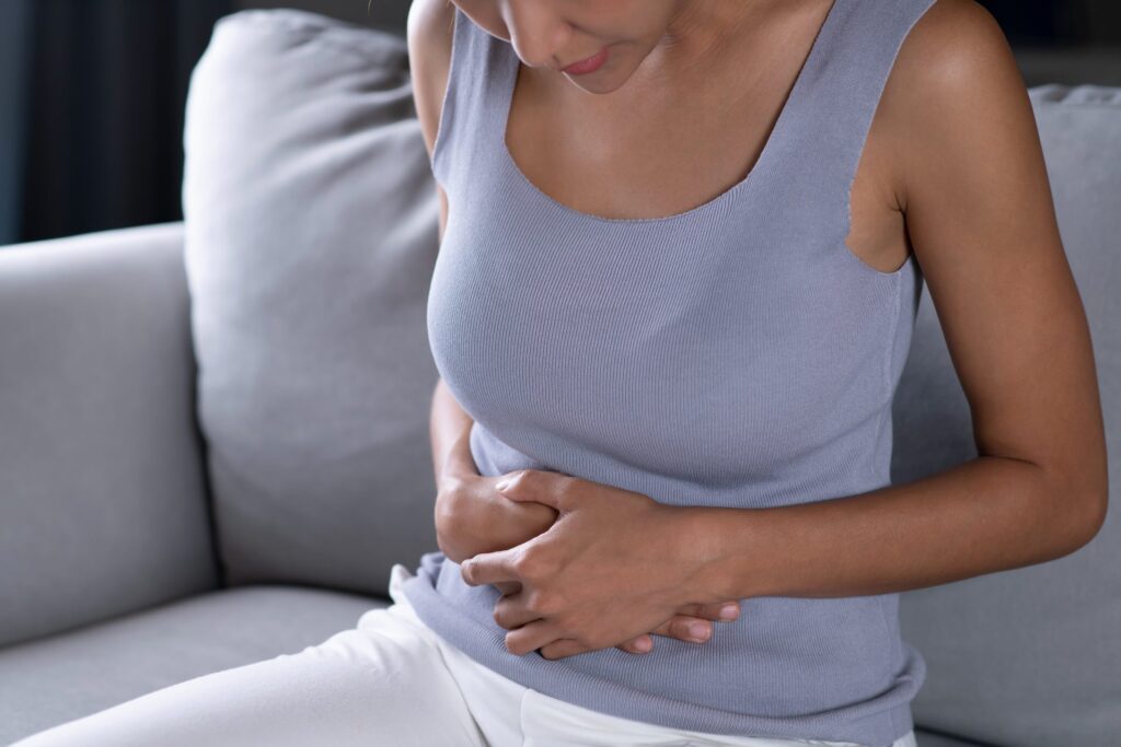 Mulher com dor abdominal intensa, um dos sintomas da colecistite aguda.