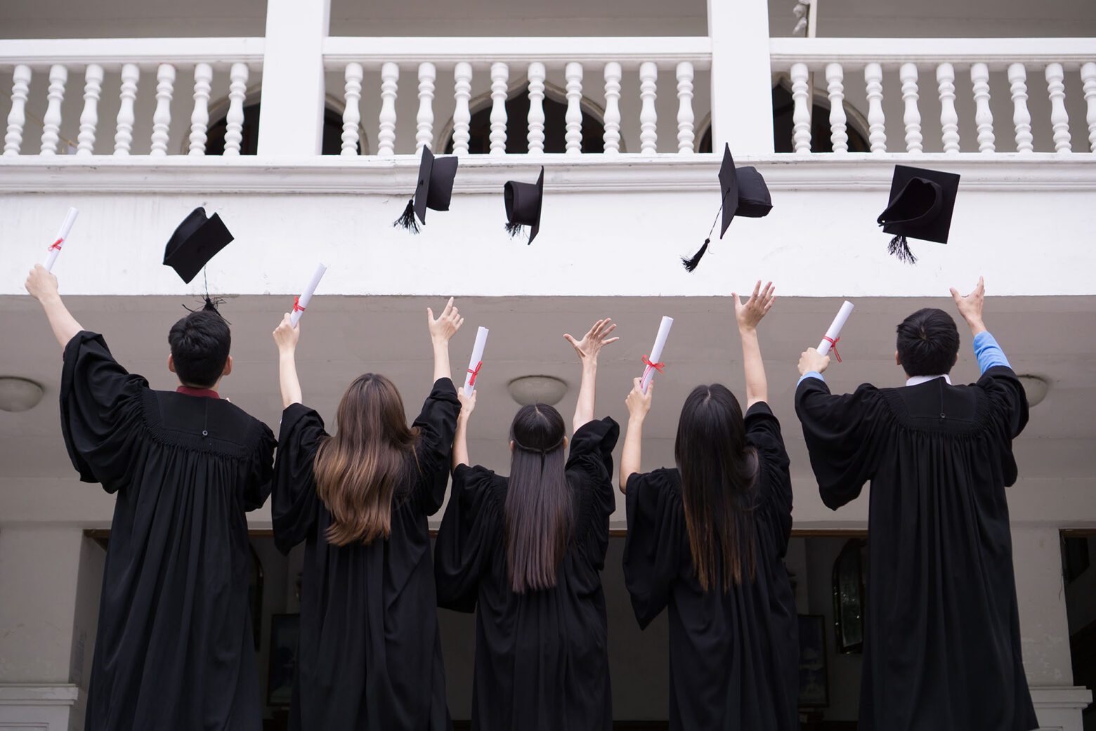 Group of Successful students with congratulations together throwing graduation hats in the air and celebrating. Education concept.